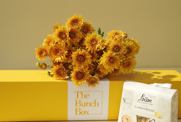 The Euro Orange Tea Break Bundle pairs the radiant energy of five Euro Orange spray chrysanthemums with the artisanal quality of 200g Loison Canestrello biscuits. Presented in a color-matched signature yellow long-form gift box, this set offers a professional and spirited gifting solution that blends high-end floristry with the heritage of premium Italian confectionery. It is a sophisticated way to share a moment of warmth and refined taste.