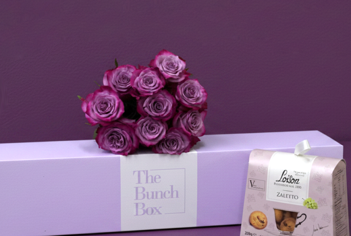 The Purple Rose Tea Time Bundle pairs ten striking deep purple roses with a 200g package of artisanal Loison Zaletto biscuits. Presented in a color-matched signature lavender gift box, this set offers a refined and modern approach to gifting that blends high-end floristry with heritage Italian pastry.